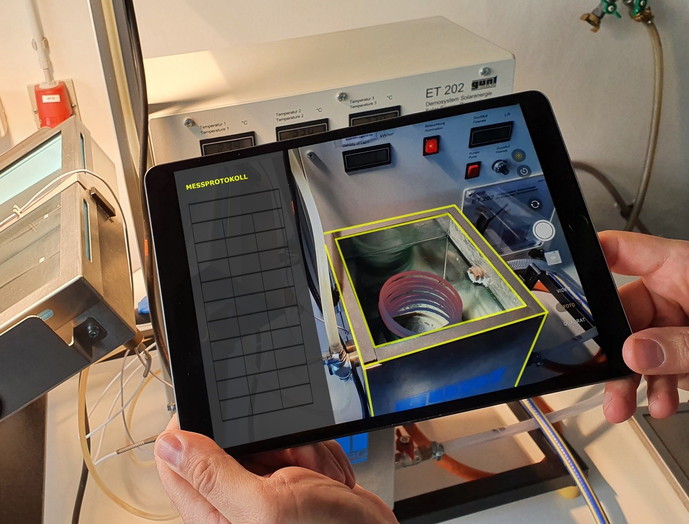 H&auml;nde halten ein Tablet, auf welchem die Thermolab-App ausgef&uuml;hrt wird.