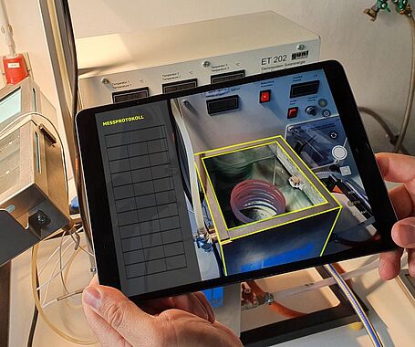 Hände halten ein Tablet, auf welchem die Thermolab-App ausgeführt wird.