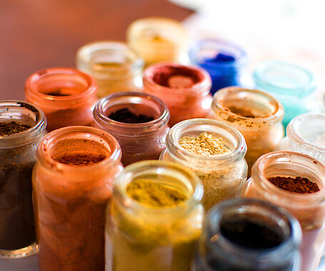 eine Ansammlung von kleinen Gläsern gefüllt mit verschiedenfarbigen Pigmenten