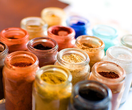 eine Ansammlung von kleinen Gläsern gefüllt mit verschiedenfarbigen Pigmenten