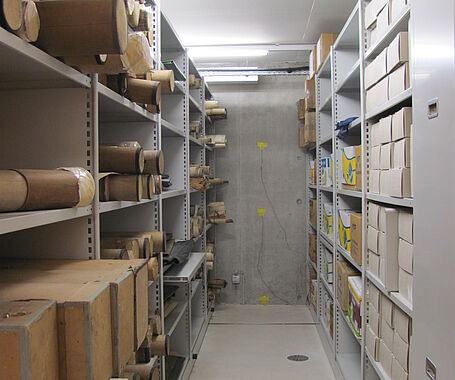 Ein Raum mit Regalen und Kisten, hellbeuchtet, an der Wand ist en Messsensor angebracht