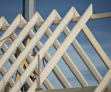Ein Dachstuhl mit Holzbalken in Nahaufnahme, blauer Himmel